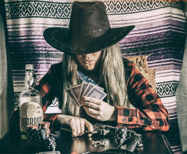 Old west cowgirl gunslinger sitting at table playing poker